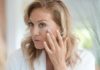 woman touching her cheek while looking in a mirror