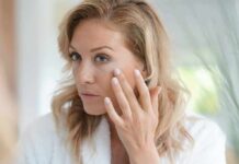 woman touching her cheek while looking in a mirror