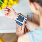 Person checking wrist blood pressure monitor indoors