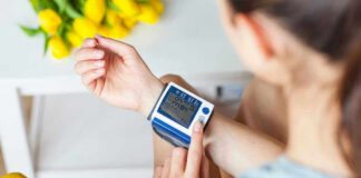Person checking wrist blood pressure monitor indoors