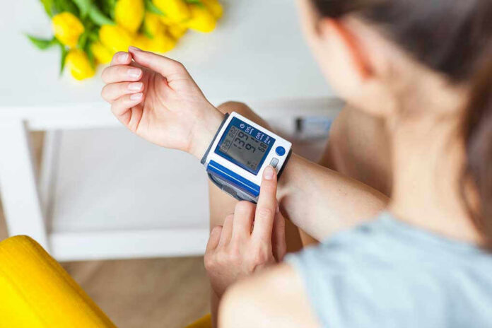 1078631948 Person checking wrist blood pressure monitor indoors