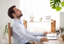 The Science of Silence: How It Rewires Our Brains Man relaxing at desk with eyes closed beside laptop
