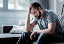 US surgeon general warns of our next public health priority Man sitting on couch with head in hand