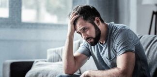 Man sitting on couch with head in hand