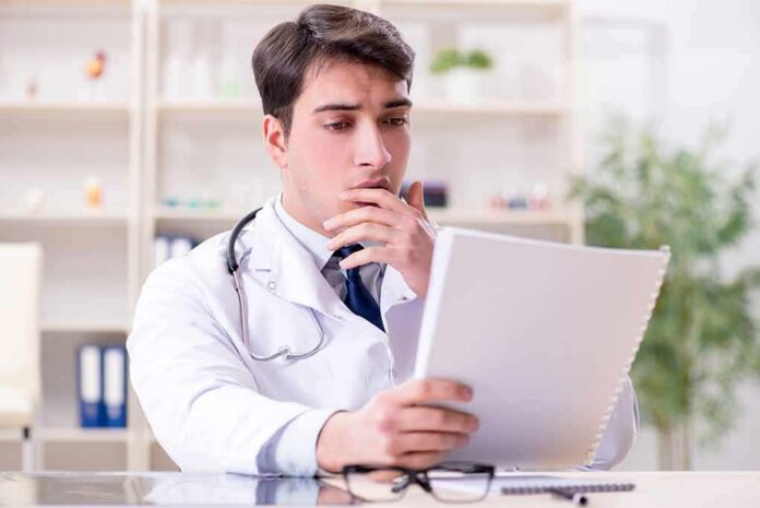 shutterstock_1100432048 Doctor reviewing a file at a desk