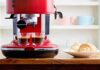 Red espresso machine brewing two shots beside croissants on a plate
