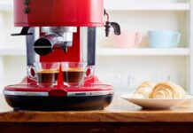 Red espresso machine brewing two shots beside croissants on a plate