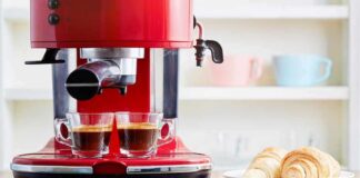 Red espresso machine brewing two shots beside croissants on a plate