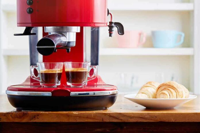 Red espresso machine brewing two shots beside croissants on a plate