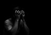 Person holding head in hands in dark lighting