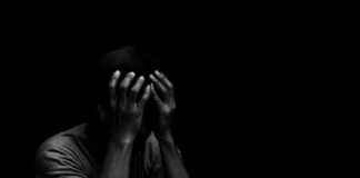 Person holding head in hands in dark lighting