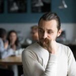 man sitting alone in a cafe looking to the side