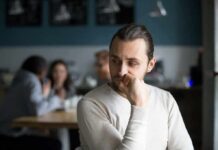 Loneliness COSTS Years – New Mega Study man sitting alone in a cafe looking to the side