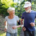 Two seniors jogging together on a forest path
