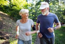 Two seniors jogging together on a forest path