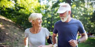 Two seniors jogging together on a forest path