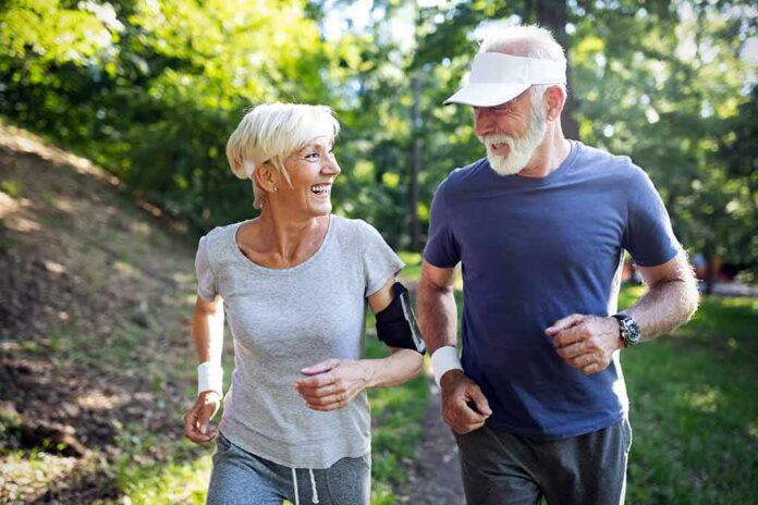 Two seniors jogging together on a forest path
