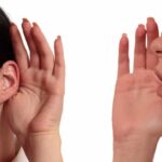 person whispering into another person's ear