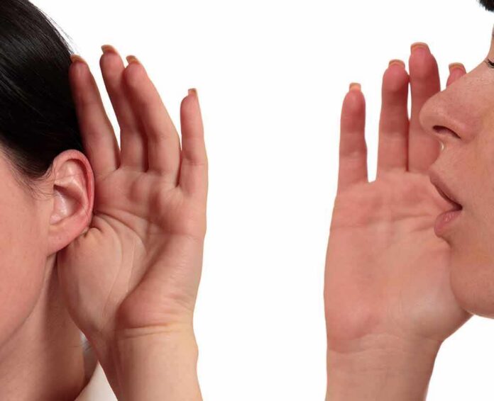 person whispering into another person's ear