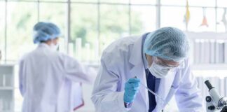 Scientist pipetting blue liquid into test tubes in a laboratory