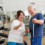 The Workout Your Brain Starts Secretly Craving After Menopause Older man and woman smiling with measuring tape in a gym