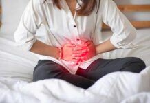 Hidden Threats Masquerading As “Normal” Cramps Woman holding her abdomen in pain while sitting on a bed