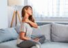 Woman sitting on couch holding her neck