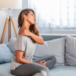 Woman sitting on couch holding her neck