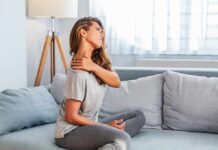 Woman sitting on couch holding her neck