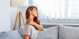 Woman sitting on couch holding her neck