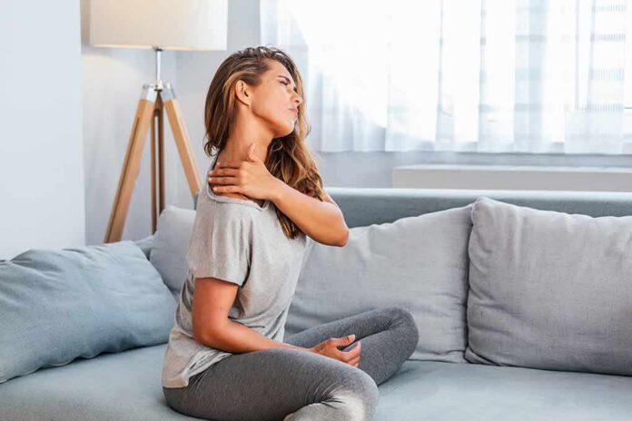 Woman sitting on couch holding her neck