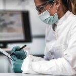 Healthcare worker in protective gear writing on a clipboard