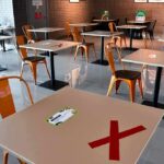 Loneliness Hack Spreads Worldwide Cafeteria with spaced tables marked with red Xs