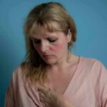 Woman touching her chest against a blue background