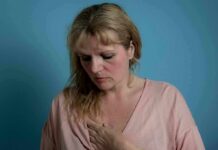 Researchers Just Linked Larger Breast Size To These 4 Conditions Woman touching her chest against a blue background