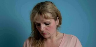 Woman touching her chest against a blue background
