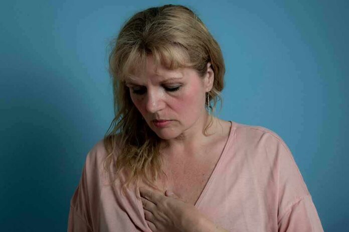 shutterstock_1756805414 Woman touching her chest against a blue background
