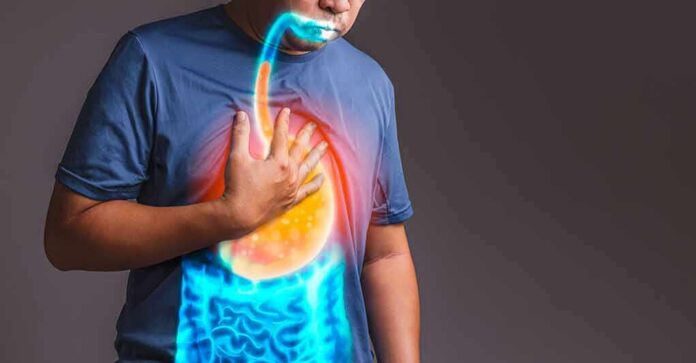 shutterstock_1817700434 Person clutching chest with illustrated reflux and stomach overlay