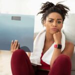 Woman holding a bathroom scale with a frustrated expression