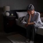 Up in the Middle of the Night? How to Fall Back to Sleep Older adult sitting on bed with head in hand