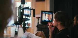 film crew member reviewing script beside monitors on set