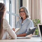 Brain Aging: Scientists Stumped By Multilingual Edge Smiling woman with gray hair talking in a modern office