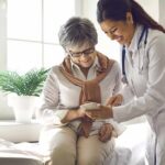Silent Epidemic: Early Menopause Signs Ignored Doctor shows smartphone to smiling older woman in clinic