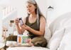 Woman reading supplement bottle label on a sofa