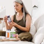 Woman reading supplement bottle label on a sofa