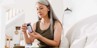 Woman reading supplement bottle label on a sofa