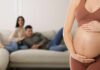 Pregnant woman holding her belly in a living room
