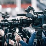 Why Fast Walkers Dodge Cognitive Decline Broadcast cameras on tripods at a press event