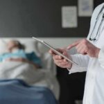 Life-Saving Surgery, Unthinkable Price Doctor using tablet beside hospital patient