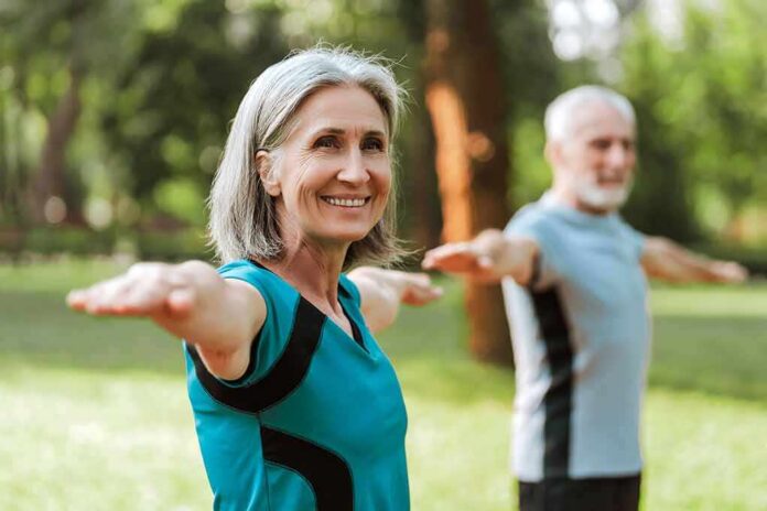 shutterstock_2520775761 Older woman exercising with arms outstretched outdoors